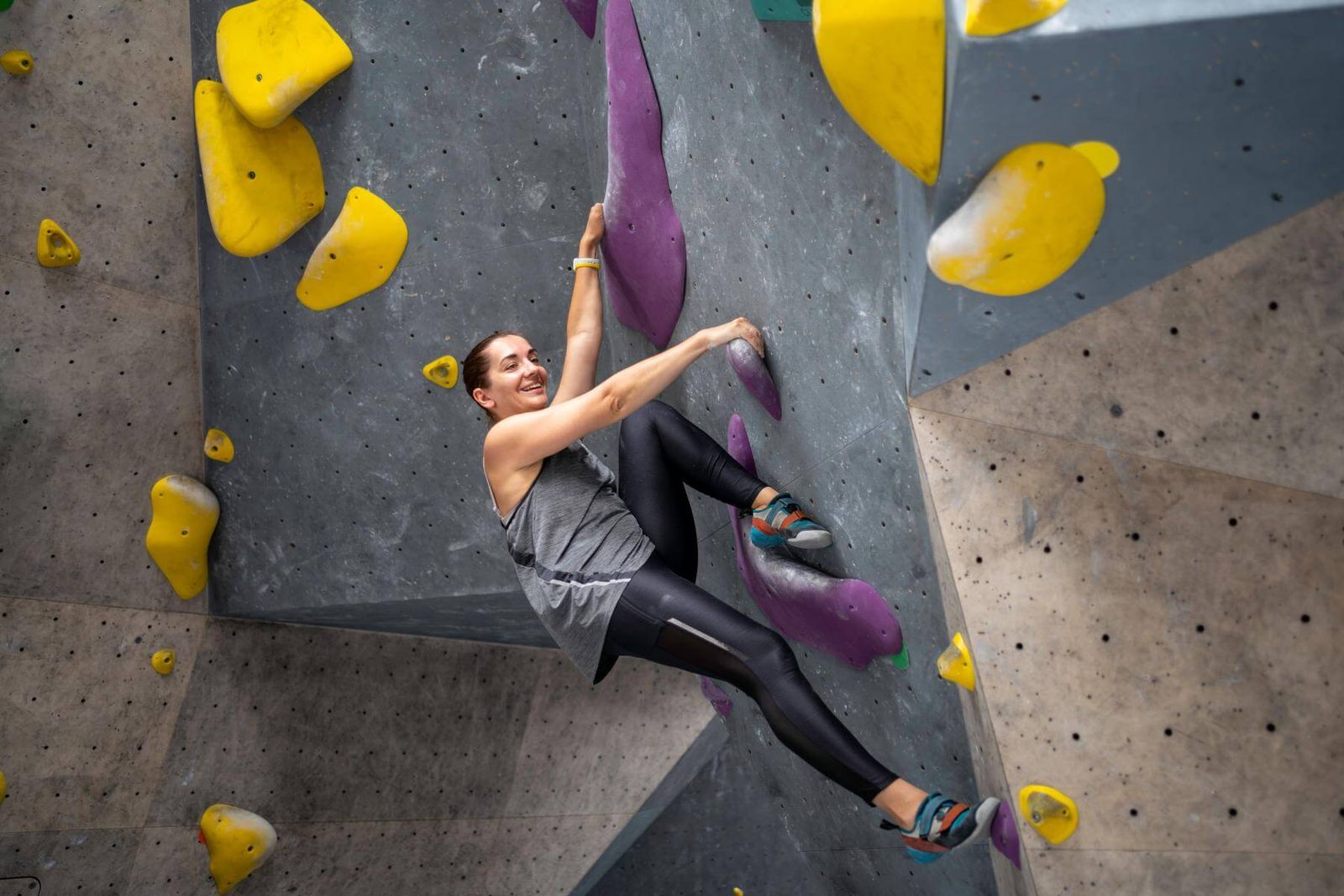 Boulderin in Leggings stellt den Fuß hoch an der Wand