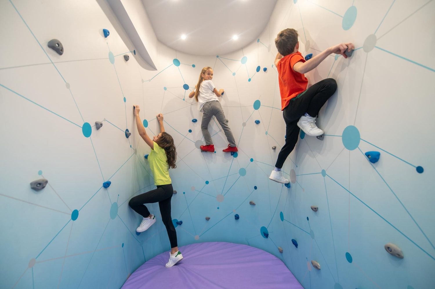 Drei Kinder klettern gemeinsam an der Boulderwand