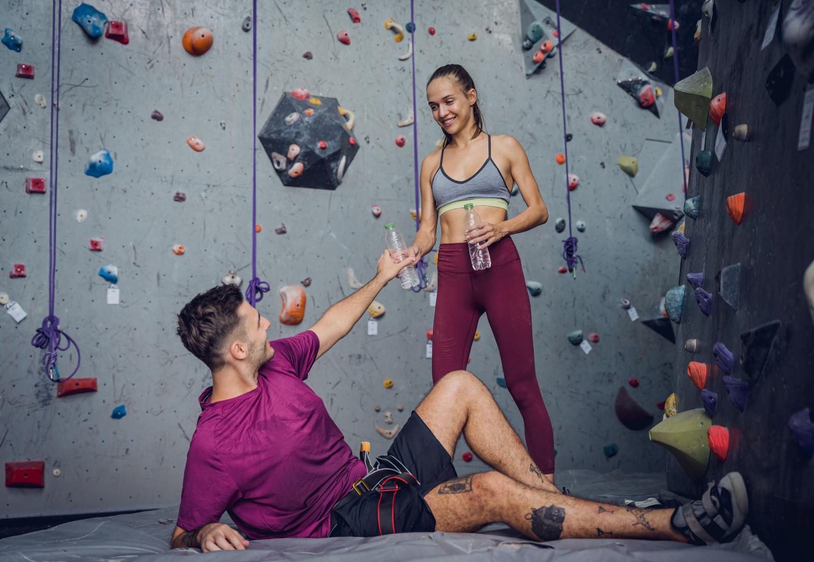 Zwei Boulderer machen Pause auf der Matte, er in Shorts und T-Shirt, sie in Leggings und Sporttop